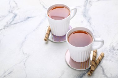 Bardak altlıklarını çay fincanlarıyla ve gofretlerle beyaz mermer masada iç.