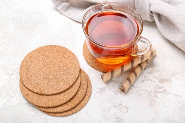 Bardak altlıklarını çay ve gofretle beyaz masada iç.