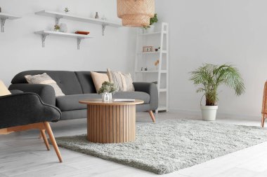 Oturma odası, siyah kanepe, koltuk ve ahşap sehpa.