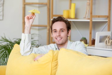 Genç adam eve kağıt uçak fırlatıyor.
