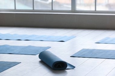 Yoga mats on floor near window in gym clipart