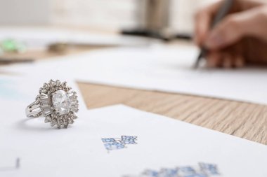 Kuyumcunun çizdiği yüzükler ahşap masada, yakın plan.