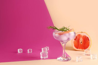 Renk arkaplanında buz küpleriyle servis edilen mor cin tonik.