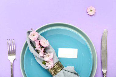 Çatal bıçak takımı, çiçek açan ağaç dalı ve katlanmış peçeteyle servis edilen güzel bir masa.