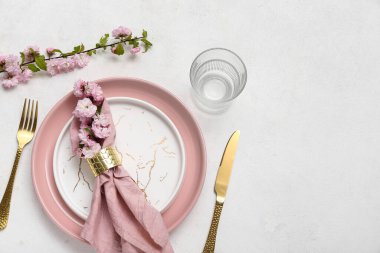 Çatal bıçak takımı, çiçek açan ağaç dalları ve beyaz arka planda katlanmış peçeteyle servis edilen güzel bir masa.