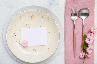 Çatal bıçaklı güzel masa servisi, çiçek açan ağaç dalı ve boş davetiye kartı beyaz arka plan