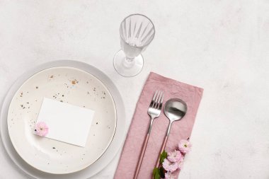 Çatal bıçaklı güzel masa servisi, çiçek açan ağaç dalı ve boş davetiye kartı beyaz arka plan