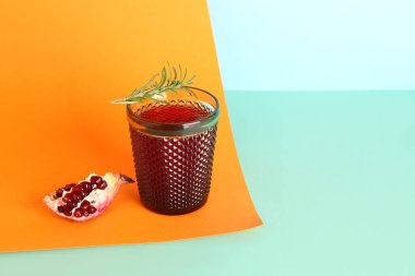 Renkli arka planda bir bardak taze nar suyu.