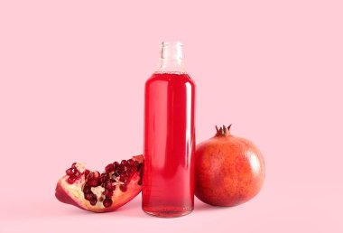 Pembe arka planda bir şişe taze nar suyu.