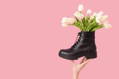 Pembe arka planda lale çiçekli kadın eli.