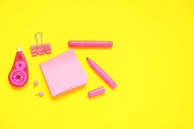 Sarı arkaplanda farklı kırtasiye malzemesi içeren yapışkan notlar.