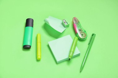 Yeşil arka planda farklı kırtasiye malzemesi içeren yapışkan notlar