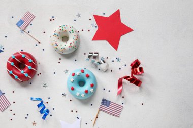 Donutlu kompozisyon, beyaz masada Amerikan bayrakları ve konfeti. Bağımsızlık Günü kutlamaları
