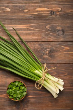 Bir demet taze soğan ve ahşap arka planda kesilmiş kase.