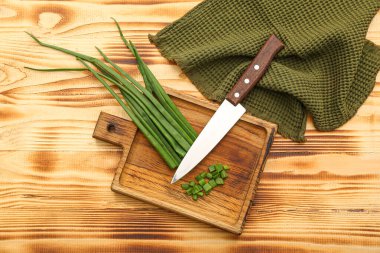 Ahşap arka planda taze kesilmiş yeşil soğanlı tahta.