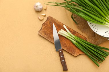 Bej arka planda taze yeşil soğanlı ahşap tahta.