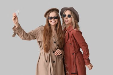 Cep telefonlu genç kız kardeşler arka planda selfie çekiyorlar.