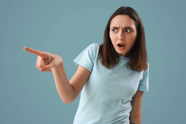 Schockierte Junge Frau Zeigt Auf Etwas Auf Blauem Hintergrund — Stockfoto