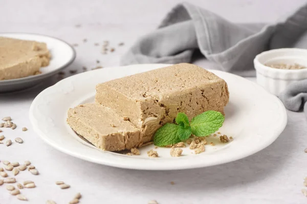 stock image Plate with tasty halva and sunflower seeds on white table