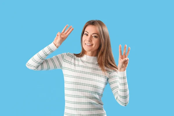Beautiful woman showing six fingers on blue background