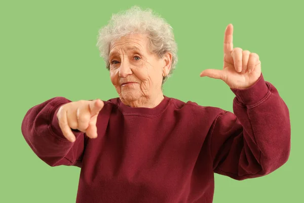 Yeşil Arka Planda Ezik Jestleri Gösteren Yaşlı Bir Kadın — Stok fotoğraf