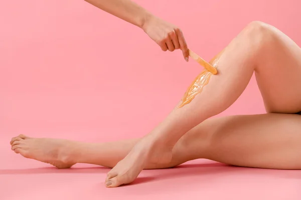 Hand Aanbrengen Van Suiker Plakken Benen Jonge Vrouw Tegen Roze — Stockfoto