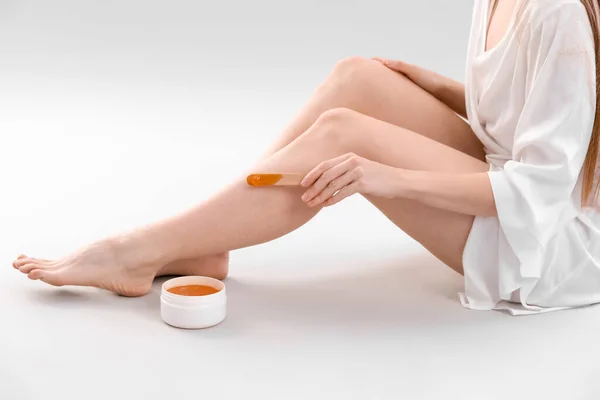 Młoda Kobieta Nakładająca Pastę Cukrową Nogi Jasnym Tle — Zdjęcie stockowe