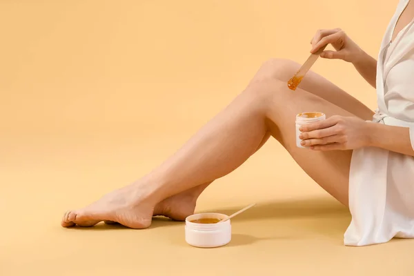 Młoda Kobieta Nakładająca Pastę Cukrową Nogi Beżowe Tło — Zdjęcie stockowe