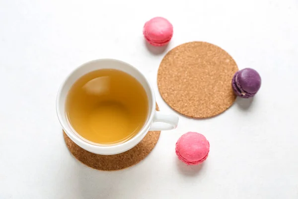 Drink coasters with cup of tea and macaroons on white table
