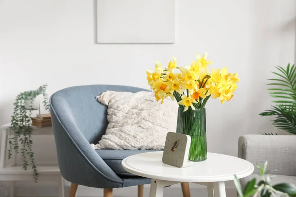 花瓶ともに咲くナルシシズムの花と時計上のコーヒーテーブルの中にリビングルーム — ストック写真