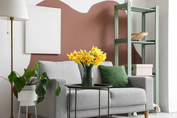 居心地の良いグレーのソファとコーヒーテーブルの上に咲くナルシシズムの花とスタイリッシュなリビングルームのインテリア — ストック写真