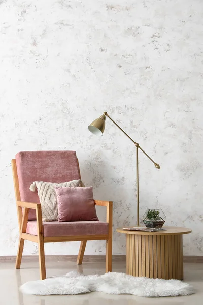 Rózsaszín Fotel Párnákkal Lámpával Floráriummal Dohányzóasztalon Fehér Grunge Fal Mellett — Stock Fotó
