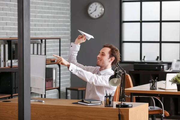 若いビジネスマンがオフィスのテーブルで紙飛行機を投げる — ストック写真