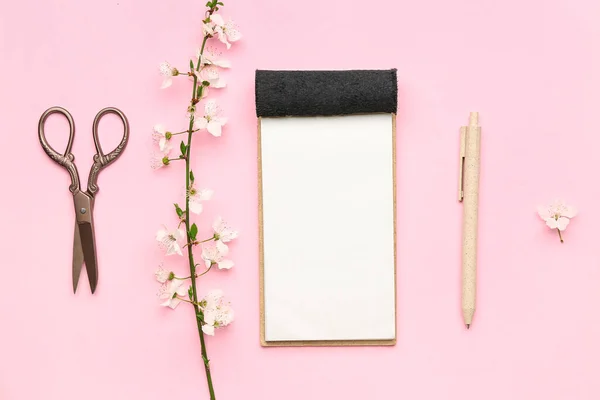 Stock image Composition with blooming tree branch, notebook, pencil and scissors on pink background