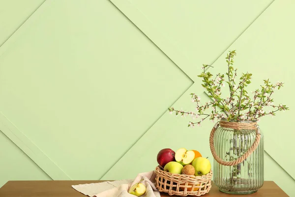 Vase Blooming Tree Branches Fruit Basket Wooden Table Green Wall — Stock Photo, Image