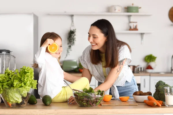Kleines Mädchen Mit Orangenscheibe Und Ihrer Mutter Der Küche — Stockfoto