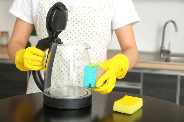 戴黄色橡胶手套的女人用海绵擦拭电水壶 — 图库照片