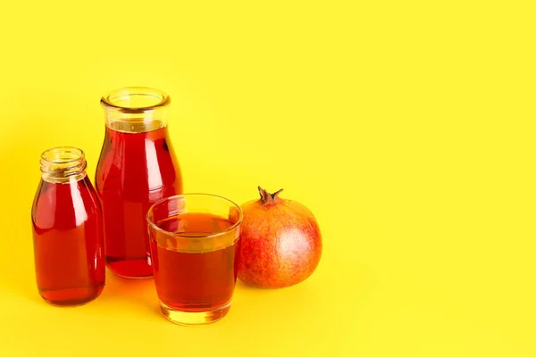 stock image Bottles and glass of fresh pomegranate juice on yellow background