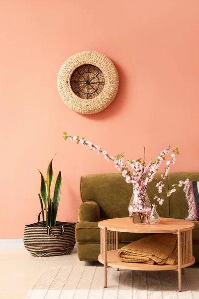 緑のソファとコーヒーテーブルの上に桜の枝が咲く居心地の良いリビングルームのインテリア — ストック写真