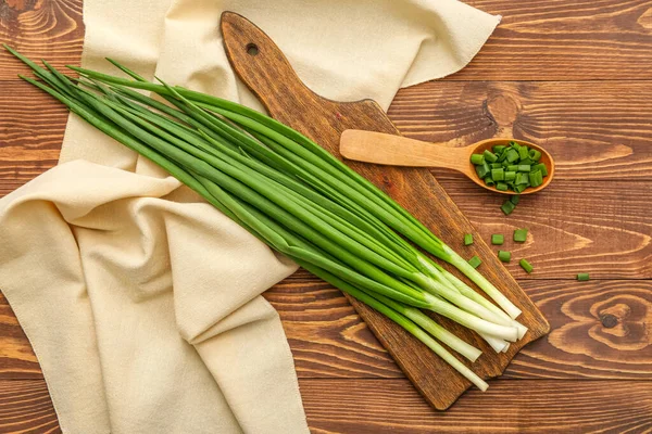 stock image Board with fresh green onion on wooden background