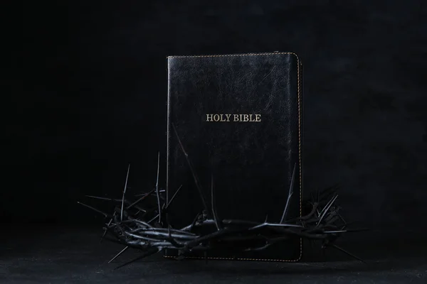 Crown of thorns with Holy Bible on black background