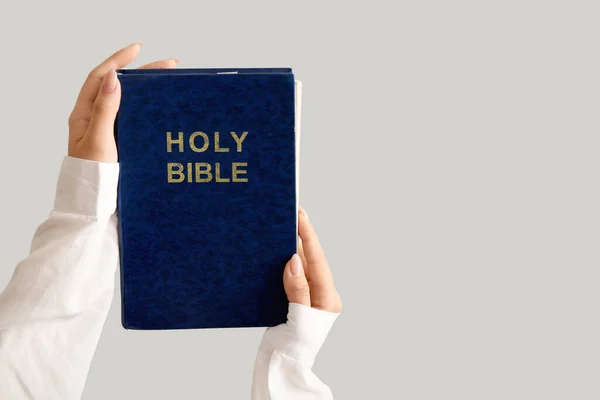 灰色の背景に聖書を持つ女性の手 — ストック写真