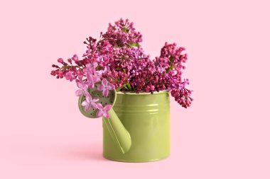 Pembe arka planda leylak dalları olan bir teneke kutu.