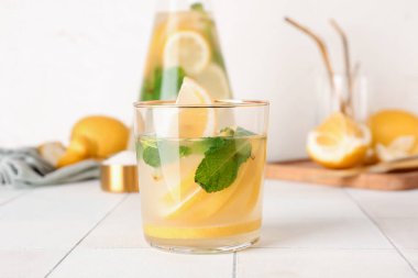 Sürahi ve cam, beyaz fayans masasında taze limonata.