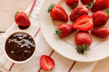 Taze çilek tabağı ve beyaz ahşap arka planda reçel.