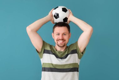 Mavi arka planda futbol topu olan adam.