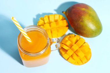 Mason kavanoz taze mango smoothie mavi arka planda, yakın plan