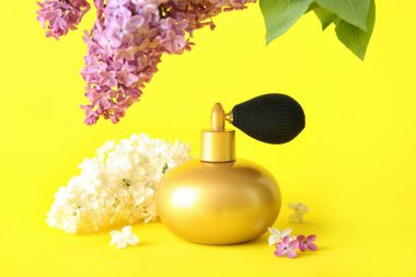 Sarı arka planda bir şişe parfümle çiçek açan güzel leylak çiçekleri.