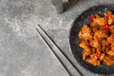 Tatlı ve ekşi tavuk kasede Gri arka planda baharatlar, yakın plan