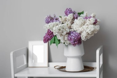 Leylak çiçekli vazo ve aydınlatma odasındaki rafta duran çerçeve.